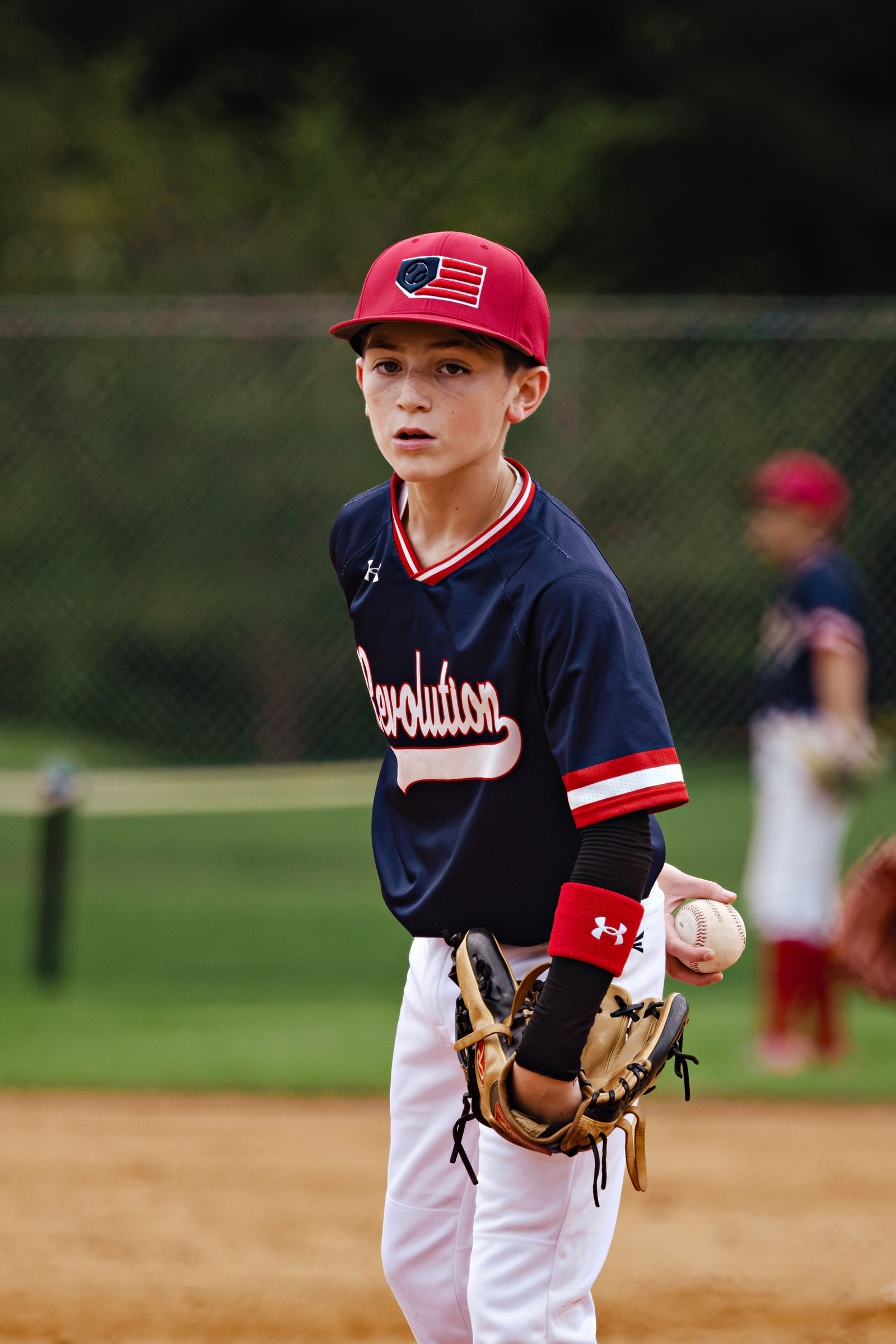 Joey Sandala on the field in a navy Revolution jersey and red cap.